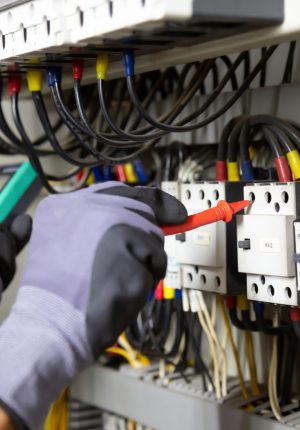 Electrician engineer tests electrical installations and wires on relay protection system. Adjustment of scheme of automation and control of electrical equipment.